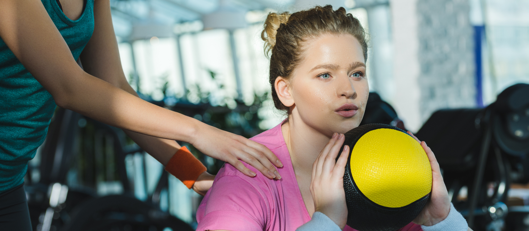 overweight woman training with medicine ball while trainer helpi
